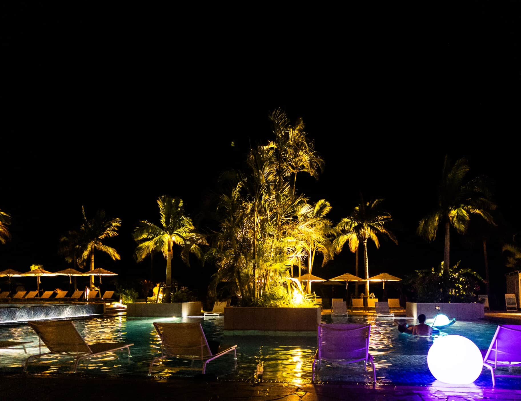 Illuminated Night Pool with Palm Trees at a Luxury Resort