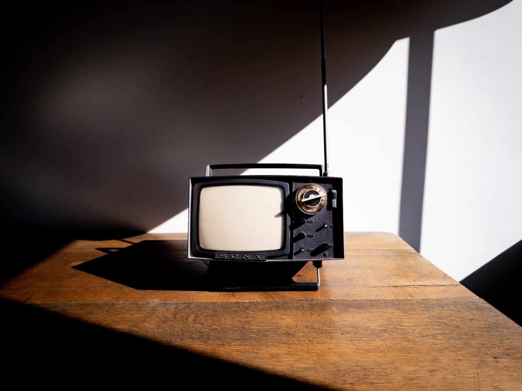 A vintage Sony portable television on a wooden surface with dramatic shadows.